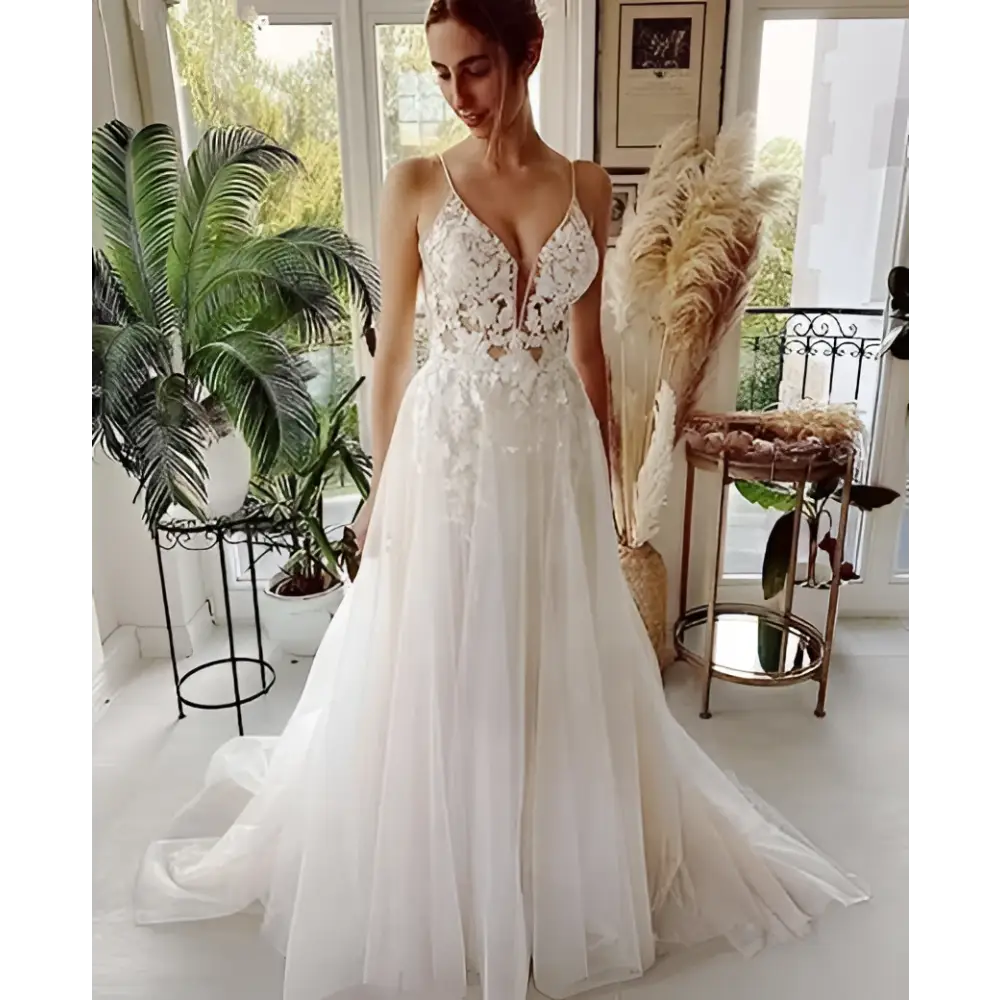 A flowing white wedding dress with lace strap backless design and intricate lace detailing with a deep v neckline