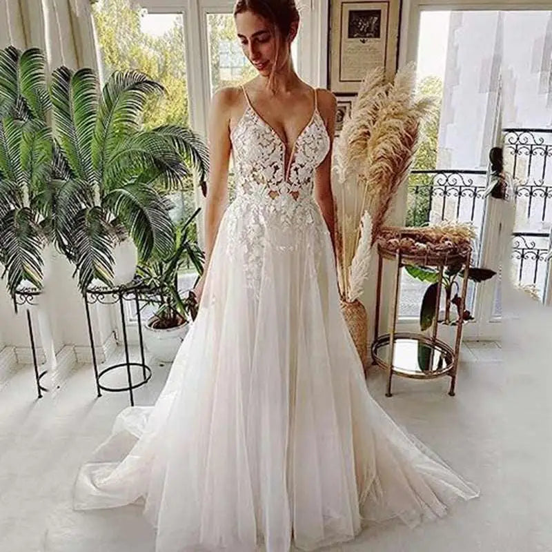 A flowing white wedding gown featuring lace strap backless design with intricate lace detailing and a deep v neckline