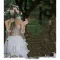 A bride wearing an elegant white lace wedding dress with sheer veil and beaded gloves in a summer couple photo shoot