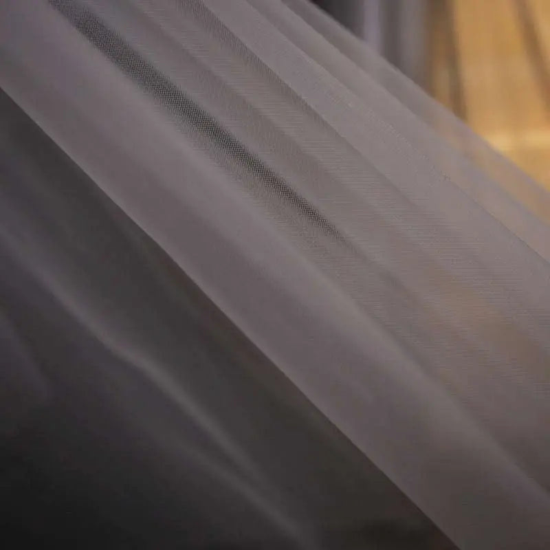 Delicate white tulle lace wedding dress fabric with subtle sheen and fine weave for trailing floral bridal veil