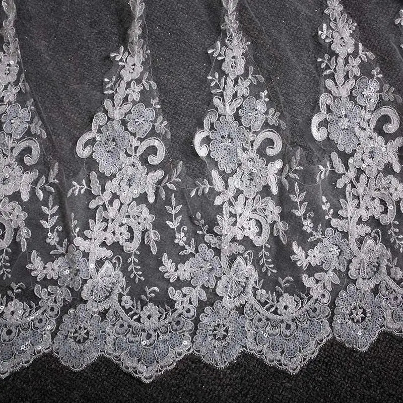 Delicate silver lace wedding dress fabric with intricate floral and vine patterns and subtle sequins on a trailing floral bridal veil
