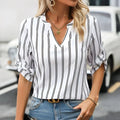 White blouse with black vertical stripes featuring a v-neckline and rolled-up sleeves in a ladies fashionable printed striped v-neck shirt