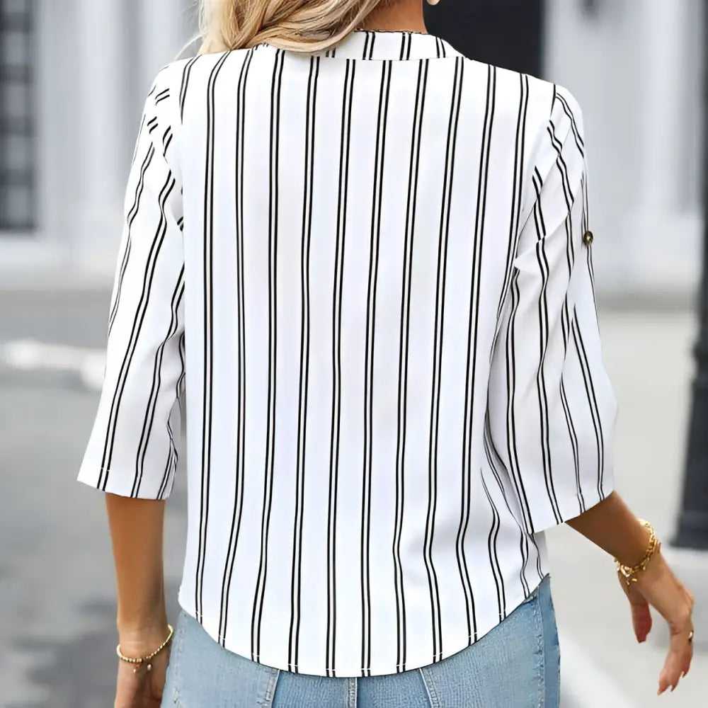 A woman wears a ladies fashionable printed striped v-neck neck shirt in white with black vertical stripes and three-quarter sleeves