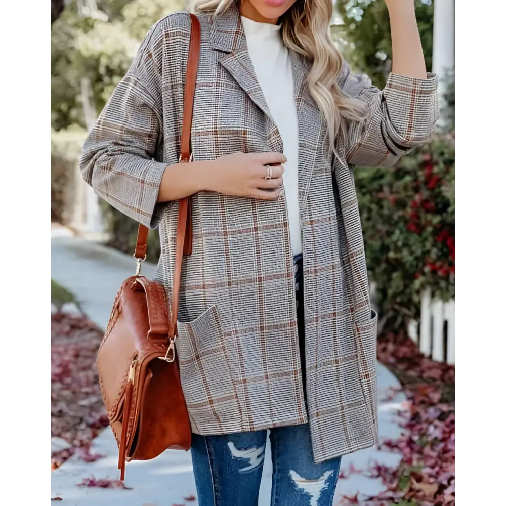 A woman wearing a gray and brown ladies plaid printed open collar blazer jacket with a classic long coat design