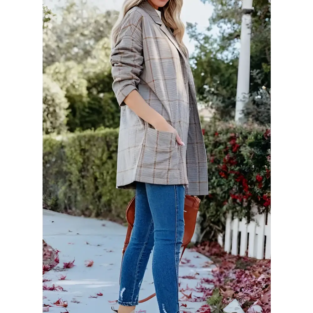 A woman wears a muted beige and brown ladies plaid printed open collar blazer with rolled-up sleeves