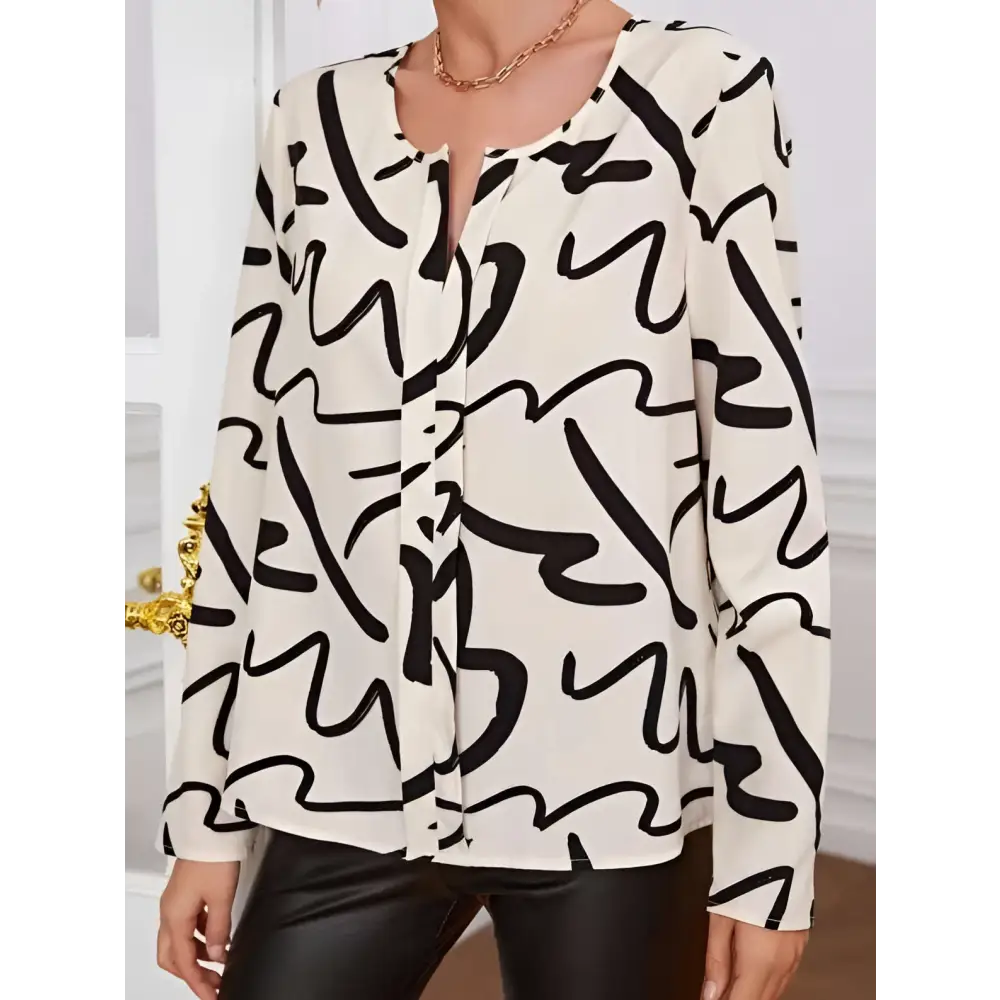 A flowing cream-colored ladies printed fashionable blouse with bold black abstract lines and long sleeves