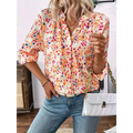 A woman wears a cream-colored lantern sleeve floral print v neck blouse with vibrant orange pink and blue flowers