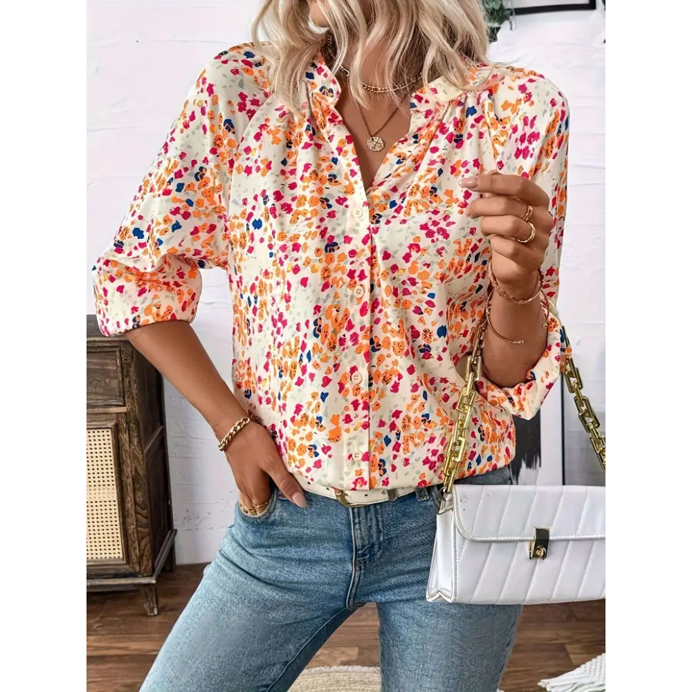 A woman wears a cream-colored lantern sleeve floral print v neck blouse with vibrant orange pink and blue flowers