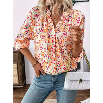 A woman wears a cream-colored lantern sleeve floral print v neck blouse with vibrant orange pink and blue flowers