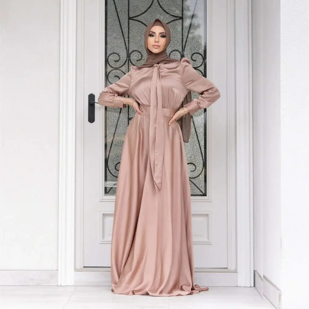 Three women wearing large hem satin long sleeve abayas in dusty rose sage green and deep burgundy colors