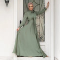 A flowing sage green large hem satin dress with long sleeves and high neckline featuring an elegant bow collar long sleeve abaya