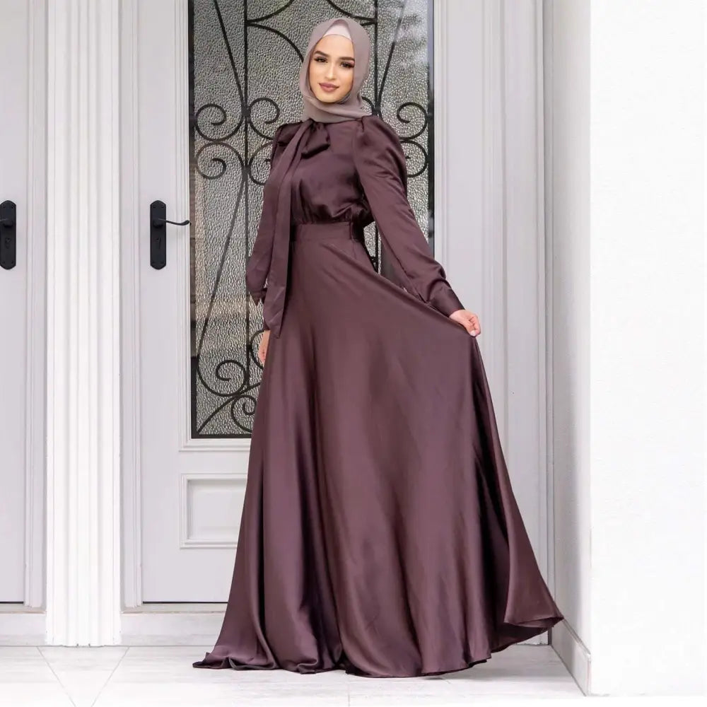 A flowing deep burgundy large hem satin dress with fitted bodice and long sleeves long sleeve abaya fashion large hem