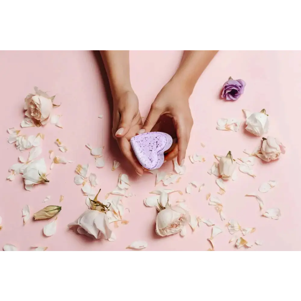 A lavender heart shower steamer with speckled texture held in hands against pink background for shower steamers gift