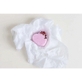 A soft pink heart-shaped bath bomb with dried rose petals in crinkled white tissue from lavender heart shower steamers gift set