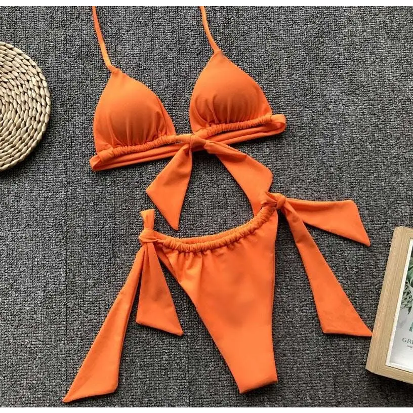 Bright orange split bikini swimsuit with tied bow details on top and bottom featuring a lavender ruched design