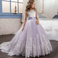 A young girl wears a lavender tulle lace wedding dress with an embellished bodice and flowing skirt for children