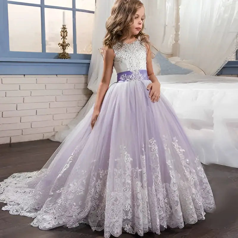 A young girl wears a lavender tulle lace wedding dress with an embellished bodice and flowing skirt for children