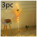 A clear transparent bobo ball luminous balloon rose bouquet with a single yellow rose and warm string lights