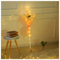 A luminous balloon rose bouquet featuring a glowing transparent bobo ball with a yellow rose and peach organza wrap