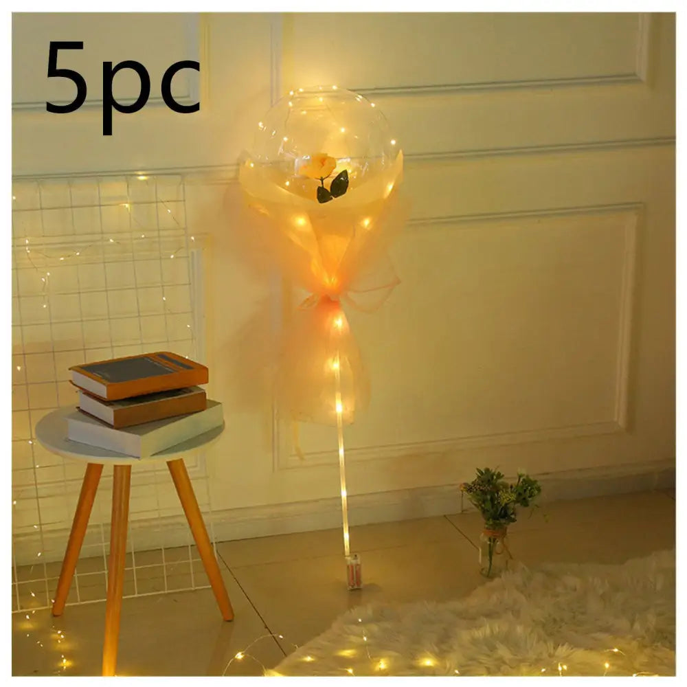 A luminous balloon rose bouquet featuring a yellow rose inside a transparent bobo ball with peach organza ribbon