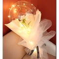 A delicate white flower inside a transparent bobo ball luminous balloon rose wrapped in sheer tulle with warm lights