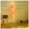 A luminous balloon rose bouquet with a pink rose inside a transparent bobo ball wrapped in peach tulle and warm lights