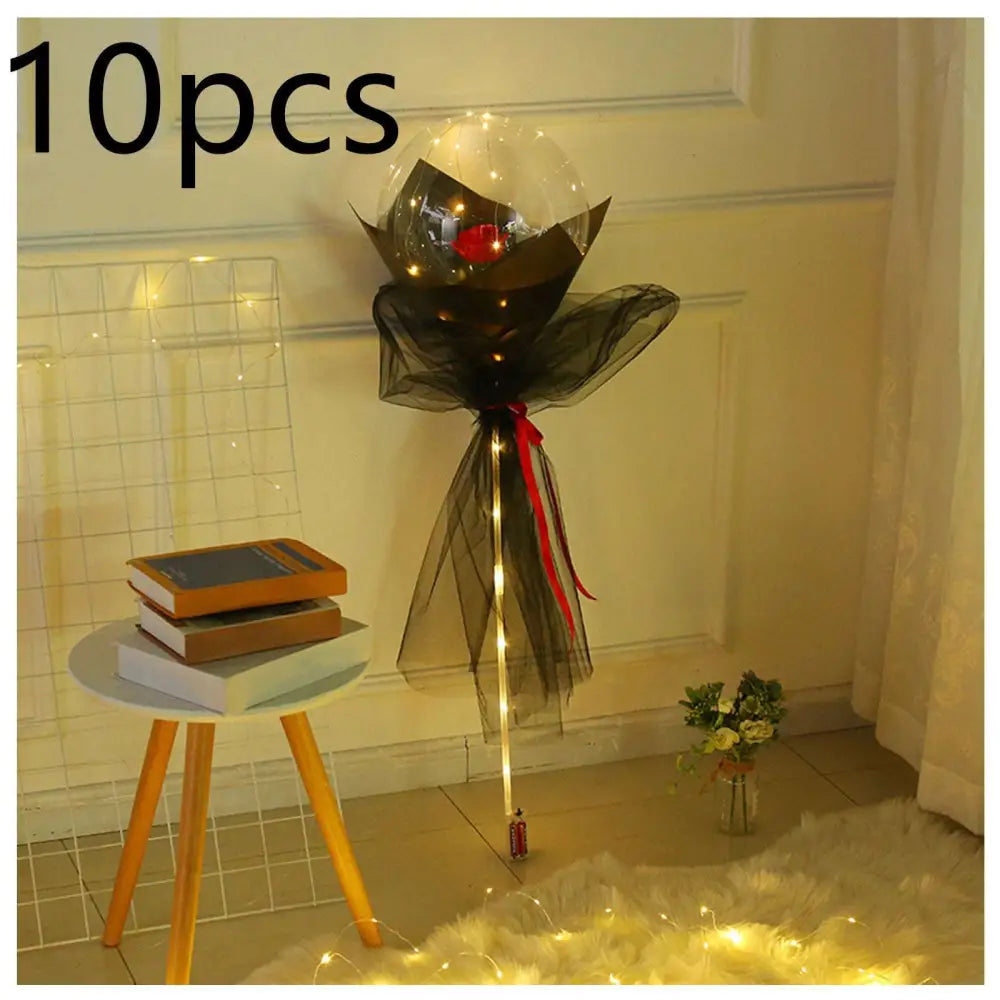 A luminous balloon rose bouquet featuring a single red rose inside a transparent bobo ball wrapped in black tulle with lights