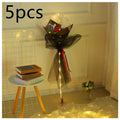 A black sheer tulle-wrapped transparent bobo ball bouquet with a luminous balloon rose inside illuminated by warm lights