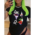 Black crew neck short sleeve t-shirt with a colorful leo graphic print featuring stylized eyes and lips in vibrant hues
