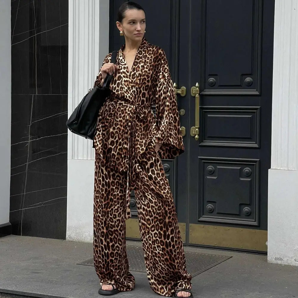 A woman wears a luxurious brown and black leopard print satin two-piece suit fashion set with wide-leg pants and bell sleeves