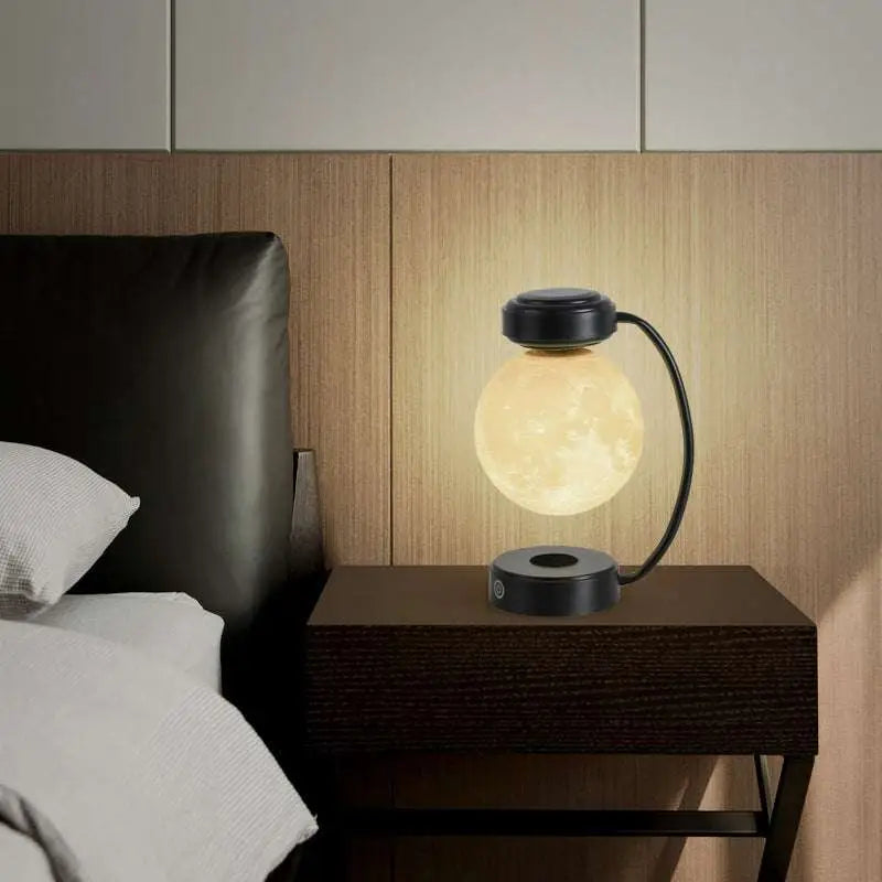 A glowing translucent levitating led moon night light with a black magnetic base and curved stand for wireless use