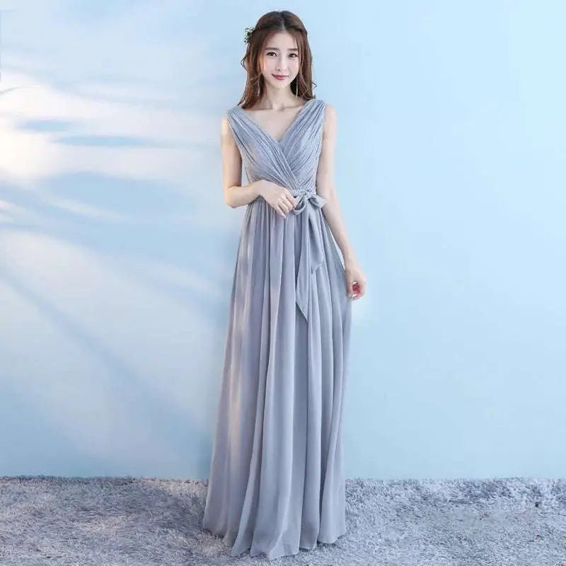 A flowing sleeveless light gray chiffon wedding bridesmaid dress with v-neckline and tied waistband for bridesmaid sisters