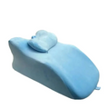 Light blue plush memory foam stomach sleeper pillow with contoured design on light green reclining chair