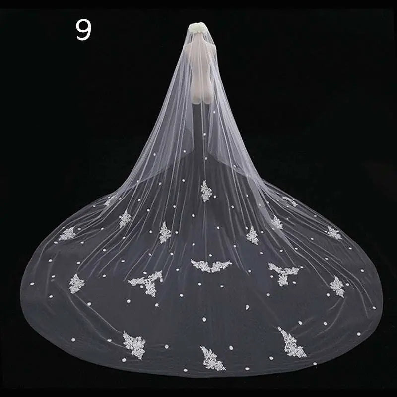 A delicate long lace wedding veil in white featuring intricate floral embroidery and pearl-like embellishments