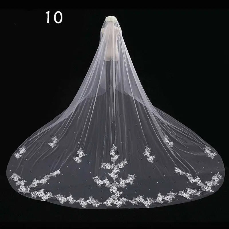 Long lace wedding veil featuring delicate white lace with intricate floral embroidery and scattered beading along the hem