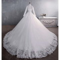 White long sleeve lace wedding dress with voluminous skirt and intricate floral embroidery bridal gown