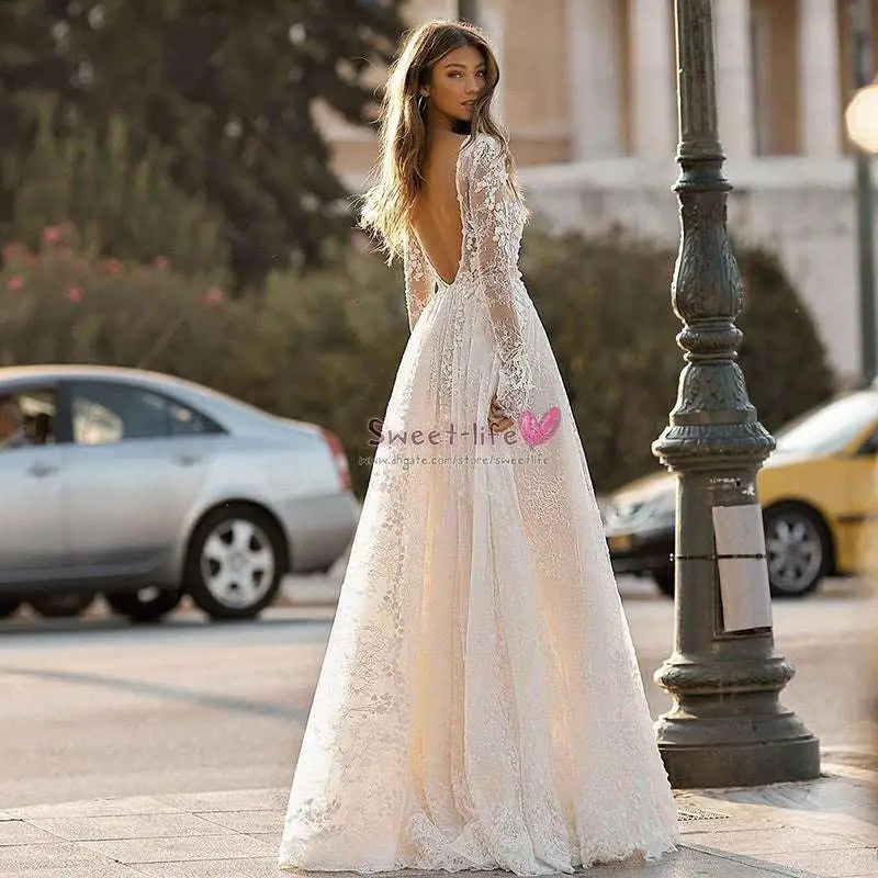A delicate white long sleeve wedding dress lace gown with a deep v neckline and flowing skirt