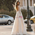 A flowing ivory wedding dress lace gown with long sleeves and a deep back cutout perfect for elegant occasions