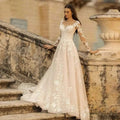 A flowing ivory lace long sleeve wedding dress mori style with intricate white floral lace on bodice sleeves and skirt