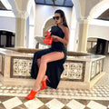 Vibrant red handbag with gold chain strap paired with black long sleeved hollow slit elastic shoulder dress