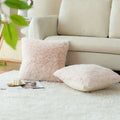 Luxurious soft faux fur throw pillow covers in pink and white resting on a plush white rug for elegant decor