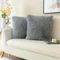 Two luxurious soft faux fur throw pillow covers in gray with a fluffy texture resting on a couch