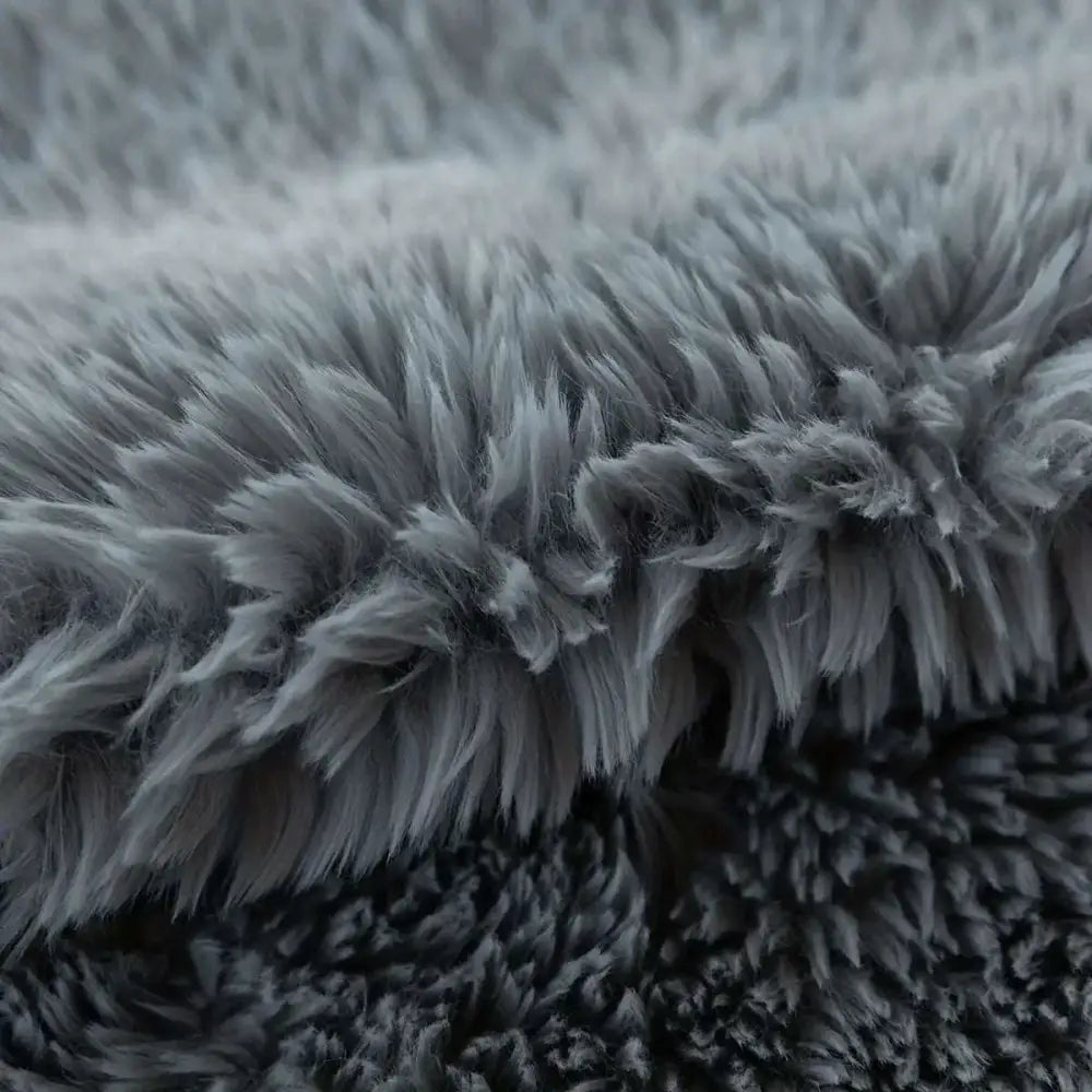 Two plush white luxurious soft faux fur throw pillow cushion covers stacked on gray blanket for cozy decor