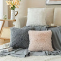 Three luxurious soft faux fur throw pillow cushion covers in gray blush pink and white on a cozy sofa