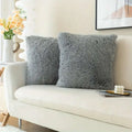 Two plush gray luxurious soft faux fur throw pillow cushion covers with a fluffy texture on a white sofa