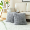 Two plush gray luxurious soft faux fur throw pillow cushion covers on a white rug showcasing their fluffy texture