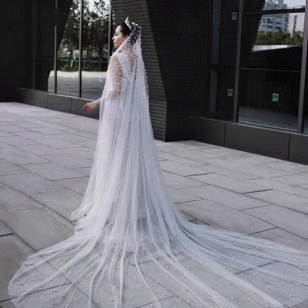 A long white industry bridal pearl veil with scattered pearl-like beads and a sparkling tiara for luxury weddings