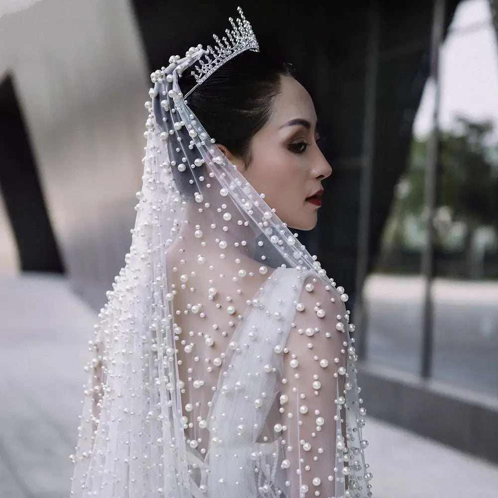 A luxury heavy industry bridal pearl tiara with intricate crystal details and a cascade of scattered pearl-like beads