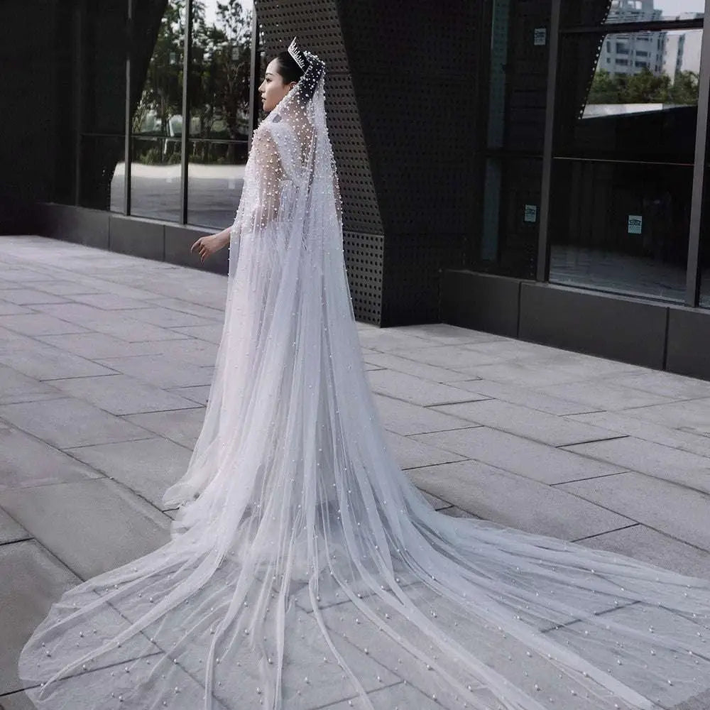 A luxury heavy industry bridal pearl veil in white adorned with scattered pearl-like beads and a sparkling tiara