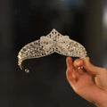 A silver forehead crown featuring intricate crystal rhinestones and pearls with a central bow for rhinestone wedding dress elegance